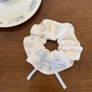 Detailed macro view of white lace scrunchie with blue ribbon bow and pearl pendant charm