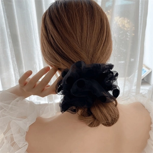 Gros plan d'un chouchou en tulle noir à pois porté sur une queue de cheval chic