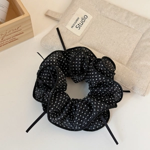 Detail of black polka dot mesh scrunchie with long ribbons on a cozy wooden background