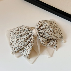 Dettaglio del fermaglio per capelli beige a fiori con piccoli ciondoli di perle