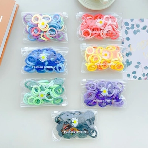 Detail of colorful elastic hair bands in seven zipper bags with small daisy charms