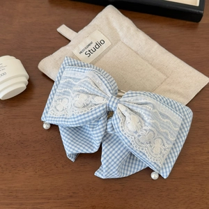Close-up of blue gingham lace hair scrunchie with pearl charms on wooden desk