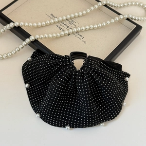 Close-up of black and white polka dot bow hair claw with elegant pearl edge detail