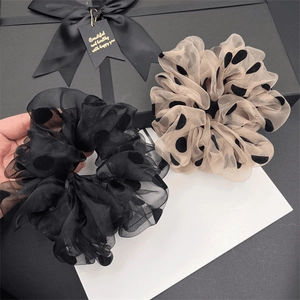 Détail des chouchous en tulle à pois noir et champagne présentés dans un coffret cadeau