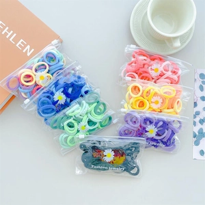 Vibrant colorful hair ties in transparent bags with floral daisy accents on blue surface