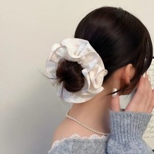 Vue détaillée du chouchou en dentelle multicouche de couleur crème sur un chignon