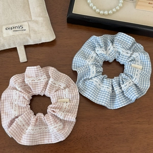 Detailed close-up of pink and blue plaid scrunchies with white lace edges on wood