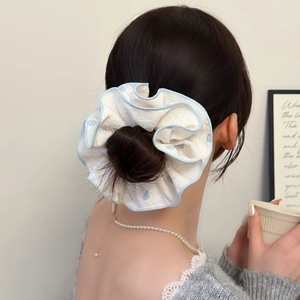 Vue détaillée d'un chouchou en dentelle blanche avec bordure bleue sur un chignon