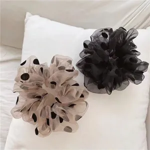 Chouchous en organza à pois noirs et beiges présentés sur un coussin blanc