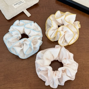 Gros plan de trois chouchous en dentelle multicouche en bleu, jaune et rose pastel