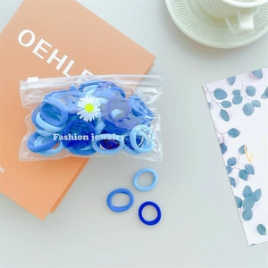 Detailed view of blue elastic hair ties with daisy charm on a stylish book setting
