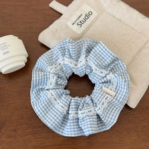 Detail of blue plaid scrunchie with white lace edges and Hand Made fabric label