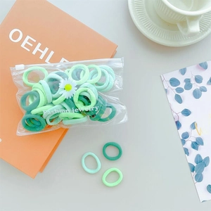 Detail of green elastic hair ties set in a clear pouch with a small daisy charm
