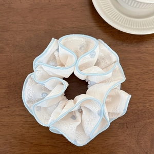 Gros plan d'un chouchou en dentelle crème avec bord bleu sur table en bois