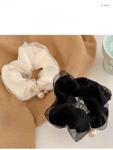 Close-up of chiffon scrunchies with elegant pearls and gold accents on a soft fabric base
