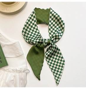 Close-up of green checkerboard silk scarf tied in a bow on elegant white fabric