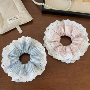 Detail of blue and pink plaid hair scrunchies with white eyelet lace trim on wood background