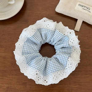 Detailed view of blue plaid hair scrunchie with layered white lace embroidery edge