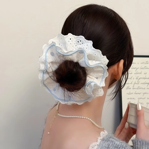 Détail d'un chouchou en dentelle blanche avec bordure bleue sur un chignon haut