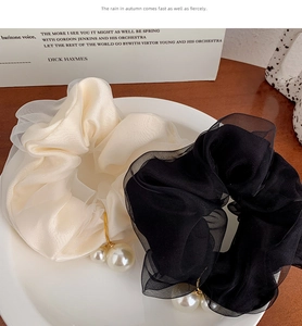 Detailed close-up of chiffon scrunchies with faux pearl charms in black and cream white