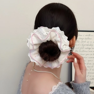 Gros plan d'un chouchou en dentelle blanche avec bordures roses sur un chignon doux