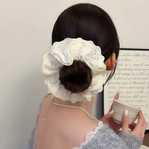 Gros plan d'un chouchou en dentelle blanche avec broderie florale et bordure jaune