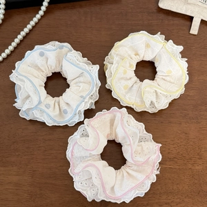 Lot de trois chouchous en dentelle aux tons bleu, jaune et rose sur bois brun