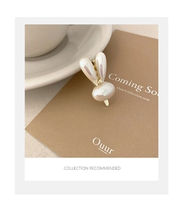 Détail d'une pince à cheveux lapin perlé sur carte avec base et clip en métal doré