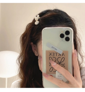 Détail d'une pince à cheveux lapin en perles élégante sur cheveux bruns bouclés au quotidien