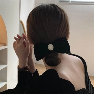 Elegant black velvet bow hair clip with oval pearl detail on back of model head
