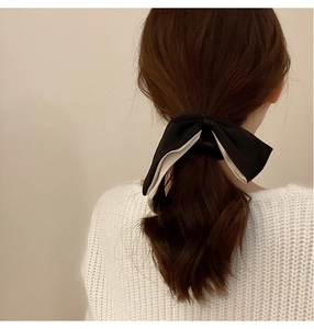 Rear view of a black and white double-layered fabric bow scrunchie on a low ponytail