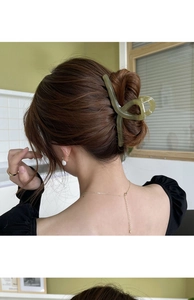 Close-up of a large avocado green hair claw clip styling long wavy brown hair
