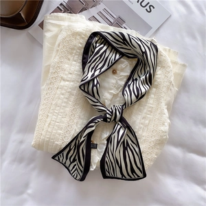 Detail of a zebra print skinny silk scarf tied in a bow on a lace collar shirt