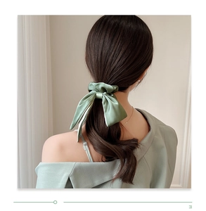 Detail of sage green silk bow hair scrunchie with long ribbons on model back