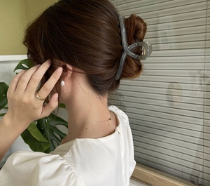 Detail view of large grey translucent hair claw clip on model's elegant bun hairstyle
