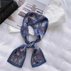 Detail of grey-blue silk scarf with cartoon cat print and red edge on a bag