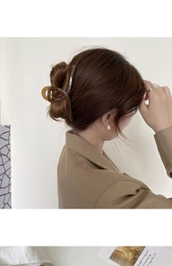 Detail of amber brown resin hair claw clip securing a low bun in minimalist French style