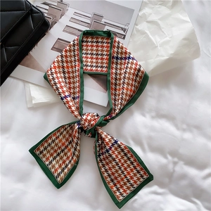 Detail of vintage French orange houndstooth silk scarf tied as an elegant hair ribbon