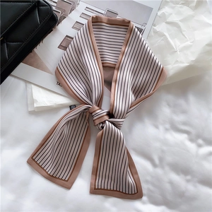 Close-up of champagne silk scarf with black stripes on a white fabric background