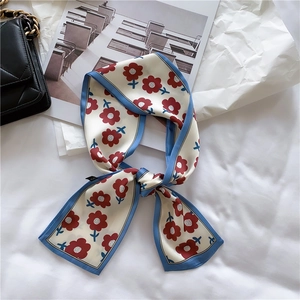 Close-up of floral print silk ribbon scarf on white fabric with fashion accessories