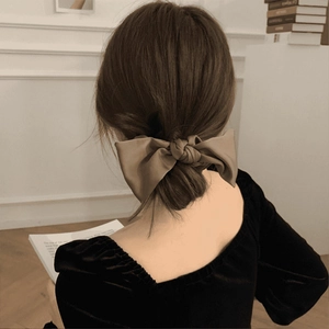 Elegant large brown satin bow scrunchie accessory styled on a bun for an autumn vintage look