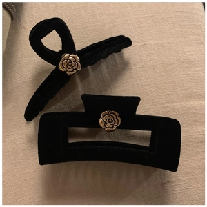 Detail view of black velvet hair clips with vintage golden camellia flower embellishments