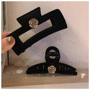 Detail of black velvet hair claw clip with golden camellia flower in vintage French style