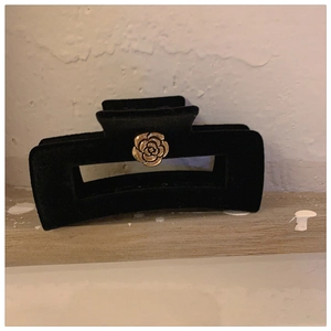 Detail of a black velvet claw clip featuring an elegant golden rose center embellishment