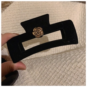 Detail of vintage black velvet hair claw clip with golden camellia flower decoration