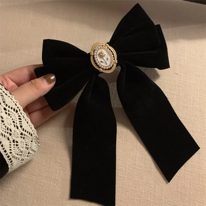 Détail d'un nœud en velours noir avec un camée floral orné de perles au centre