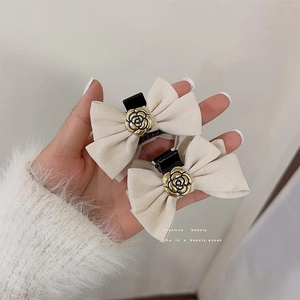 Close-up of beige velvet bow hair clips with golden camellia flower metal accents