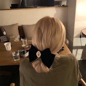 Détail d'un grand nœud en velours noir avec relief de rose sur de longs cheveux blonds