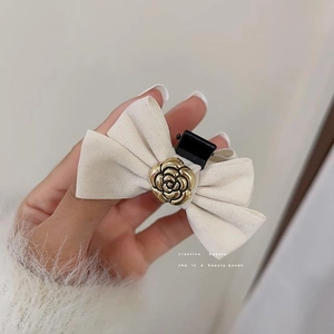 Close-up of beige velvet bow hair clip with a golden camellia flower center detail