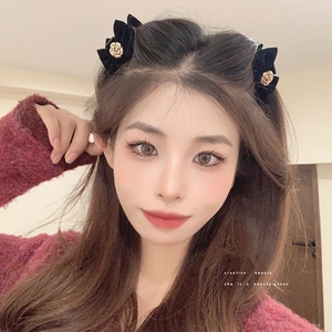 Pair of black velvet bow hair clips with gold rose detail shown on a model